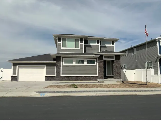 Prairie-style house with a gate, an attached garage, concrete driveway, and stone siding