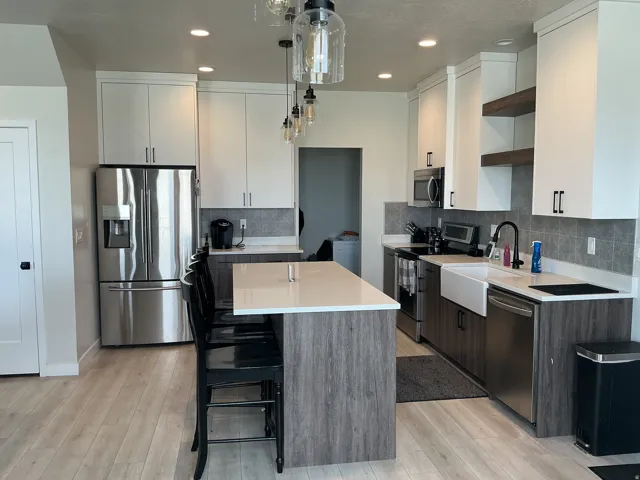 Kitchen featuring two tone color scheme, stainless steel appliances, a kitchen breakfast bar, tasteful backsplash, and a center island