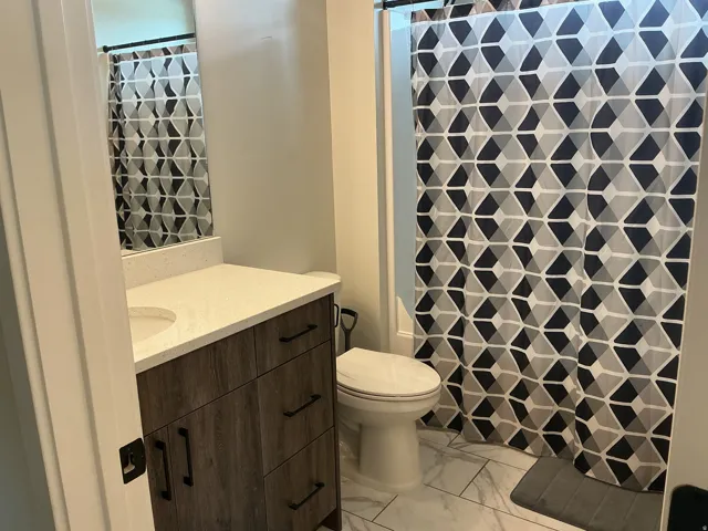 Full bath featuring vanity, a shower with curtain, and light marble finish floors
