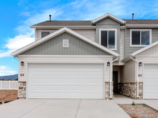 View of front of house with stone siding, roof with shingles, concrete driveway, and a garage