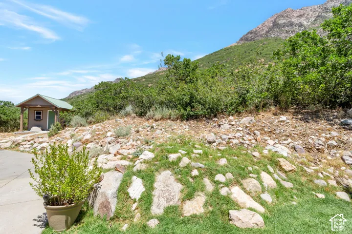 Mountainous terrain featuring a small outbuilding with a green metal roof, a paved surface, and natural rock landscaping