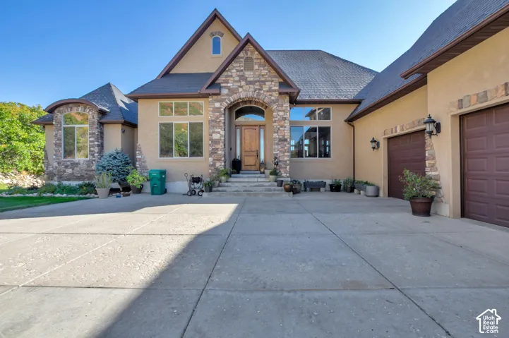Stucco exterior with stone accents, arched entryway, and multiple garage doors
