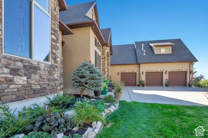Three-car garage with individual doors, dormer window, and paved driveway