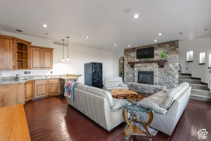 Living area featuring recessed lighting, dark wood-type flooring, and a stone fireplace