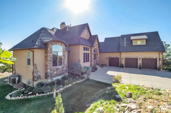 Stucco exterior with stone accents, arched window, and a three-car garage