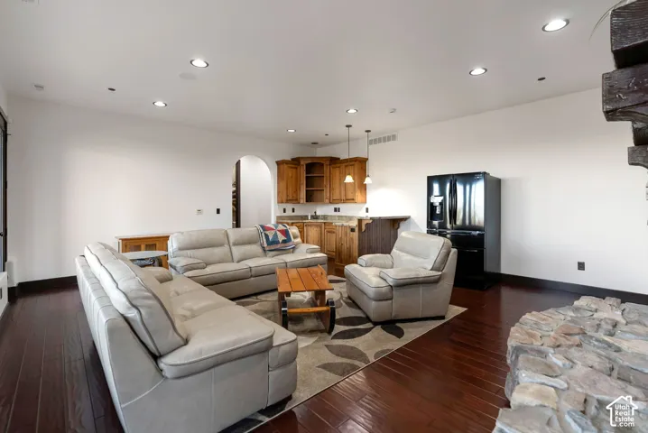 Living area featuring arched walkways, recessed lighting, and dark wood-style floors