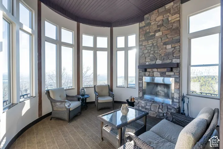 Living area with a fireplace, a high wooden ceiling, healthy amount of natural light, and carpet