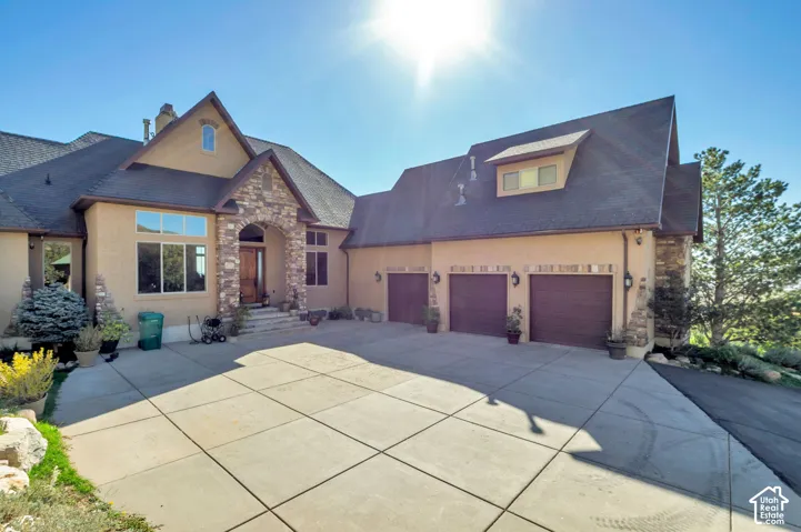 Stucco exterior with stone accents, a multi-car garage, and a large concrete driveway