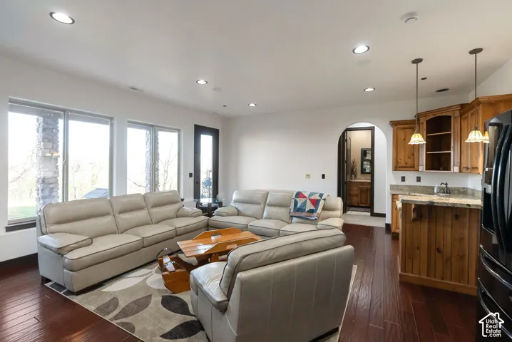 Living room featuring arched walkways, dark wood-style floors, and recessed lighting