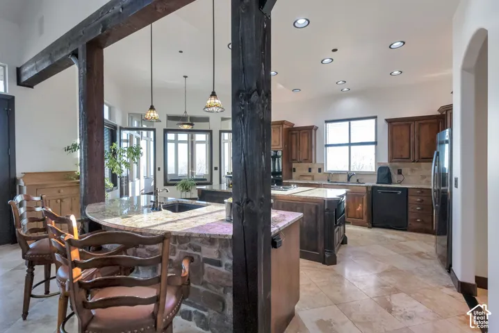 Kitchen with tasteful backsplash, dishwasher, freestanding refrigerator, and light stone countertops