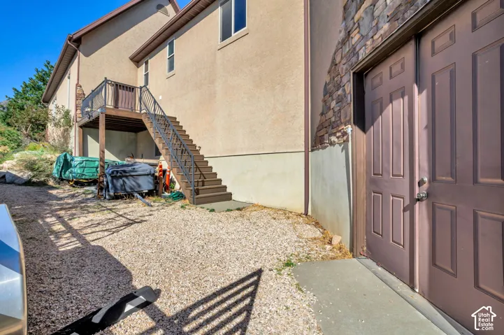 Exterior access with a gravel ground surface, a neutral-toned stucco facade, and a stone accent wall