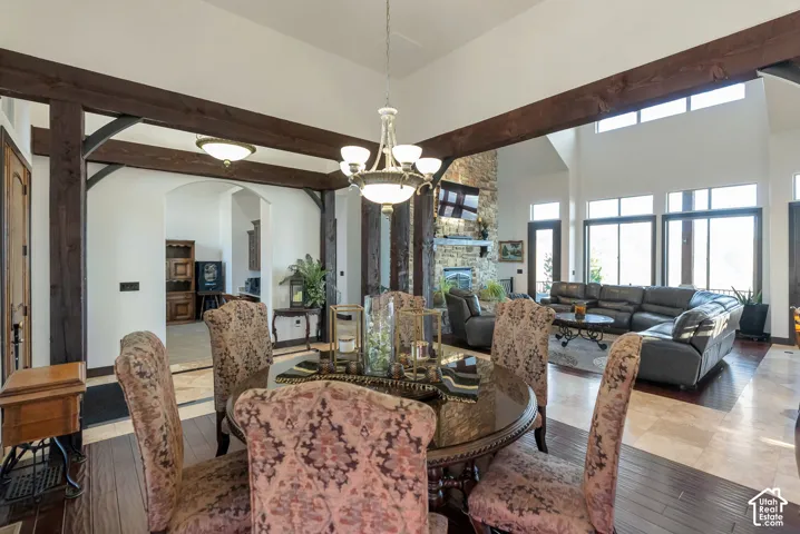 Dining space with suspended lighting, arched walkways, wood-type flooring, a fireplace, and a high ceiling