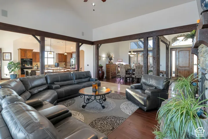 Living room featuring dark wood-style flooring, lofted ceiling, a ceiling fan, arched walkways, and suspended lighting