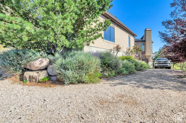 Stucco exterior with multiple windows, prominent chimney structure, and a gravel driveway