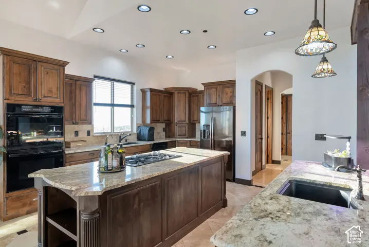 Kitchen with arched walkways, a kitchen island, open shelves, tasteful backsplash, and dark wood finish cabinetry