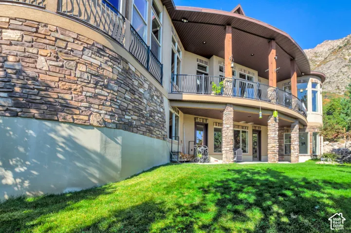 Stone veneer exterior with a curved balcony, wrought iron railing, and large windows