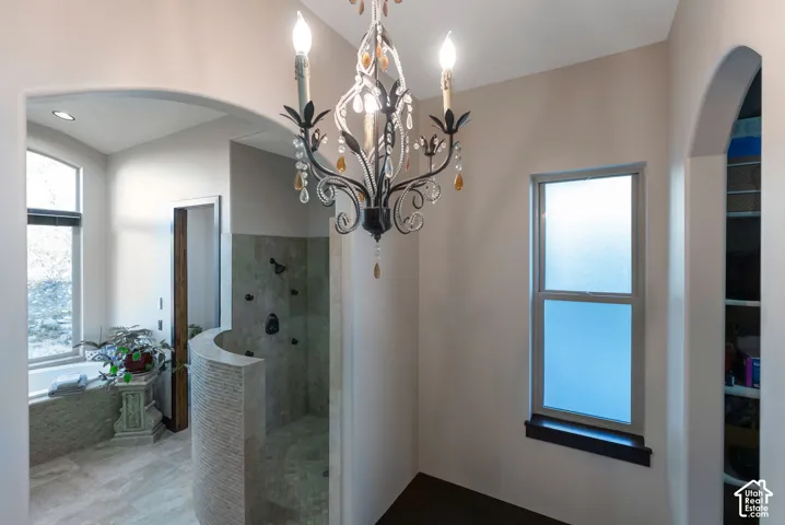 Bathroom featuring a walk in shower, a garden tub, and hanging lights