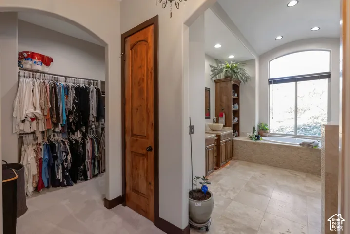 Bathroom with vanity, recessed lighting, a garden tub, a barrel ceiling, and a walk in closet