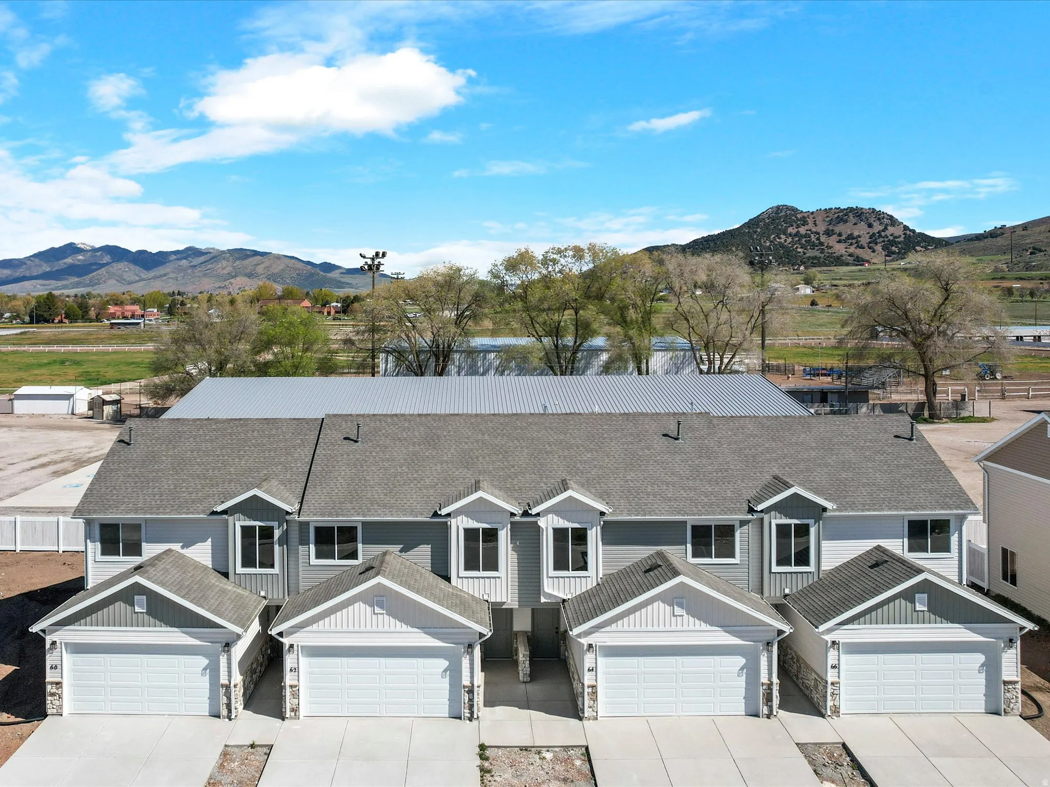 View of front facade with stone siding, board and batten siding, concrete driveway, a mountain view, and roof with shingles