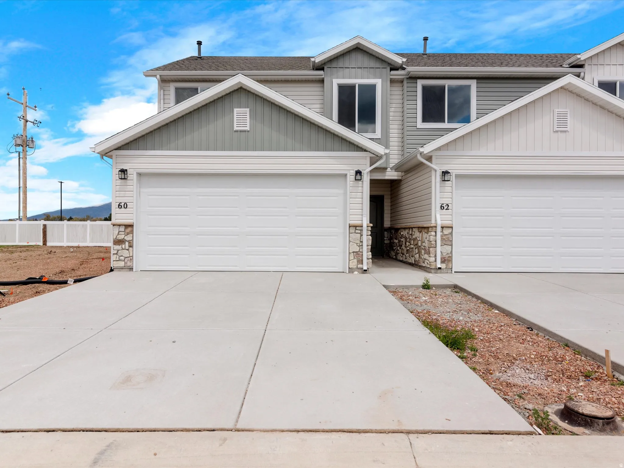 View of front of house with stone siding, driveway, and a shingled roof
