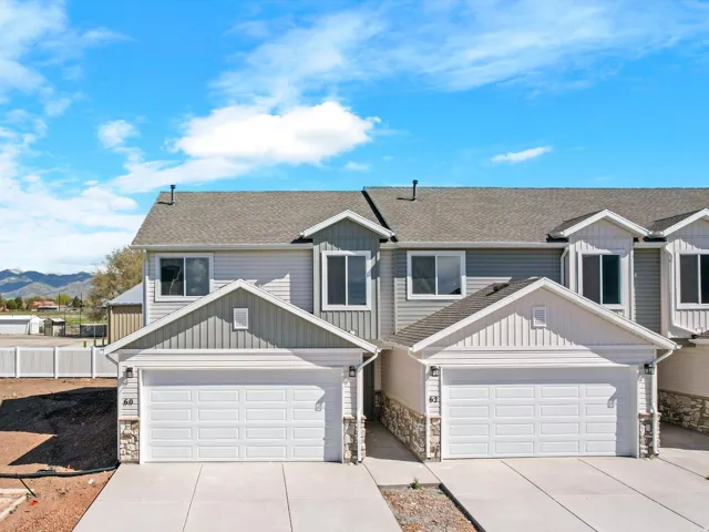 View of front of home with a shingled roof, stone siding, board and batten siding, driveway, and an attached garage