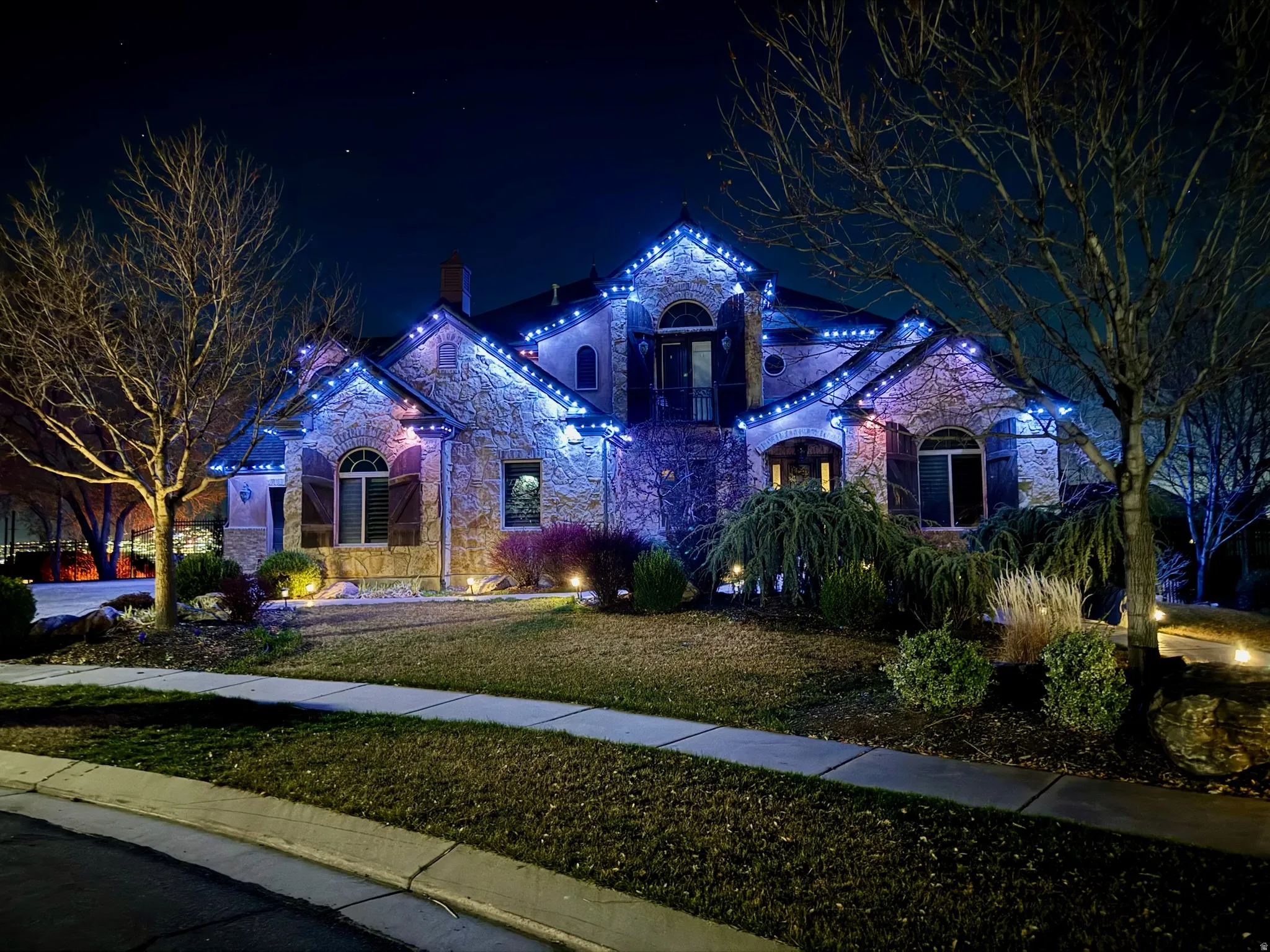 View of front of home featuring stone siding and a yard