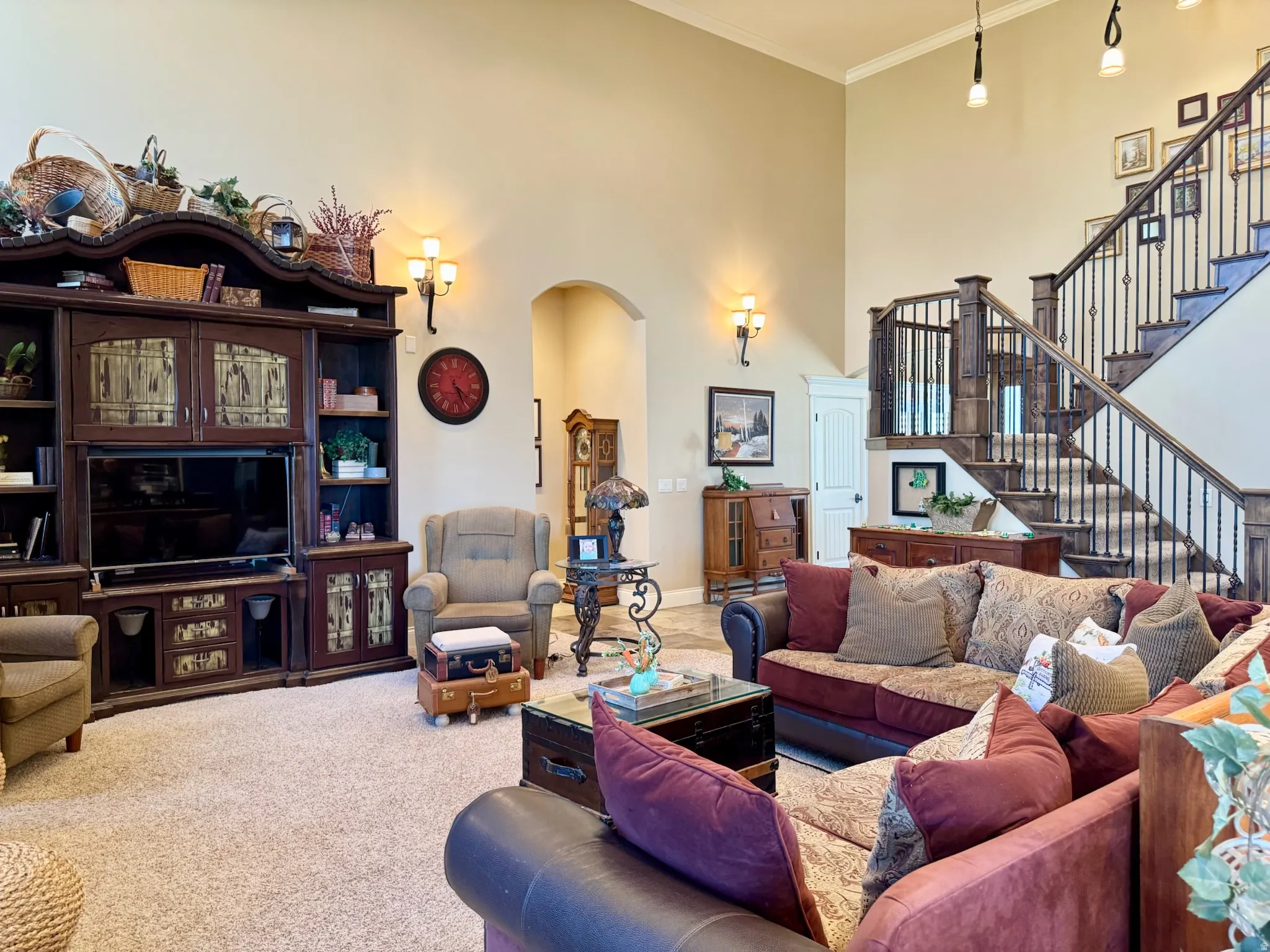 Carpeted living area with a high ceiling, arched walkways, and ornamental molding
