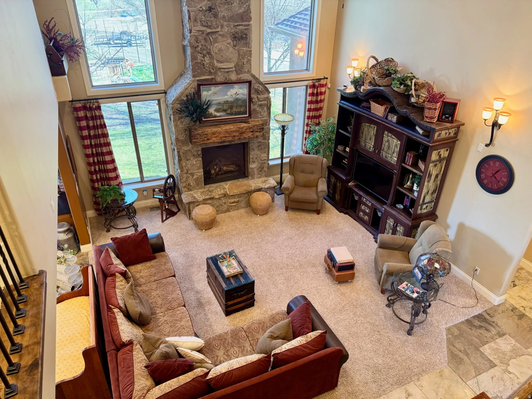 Living area featuring a high ceiling, a stone fireplace, and carpet