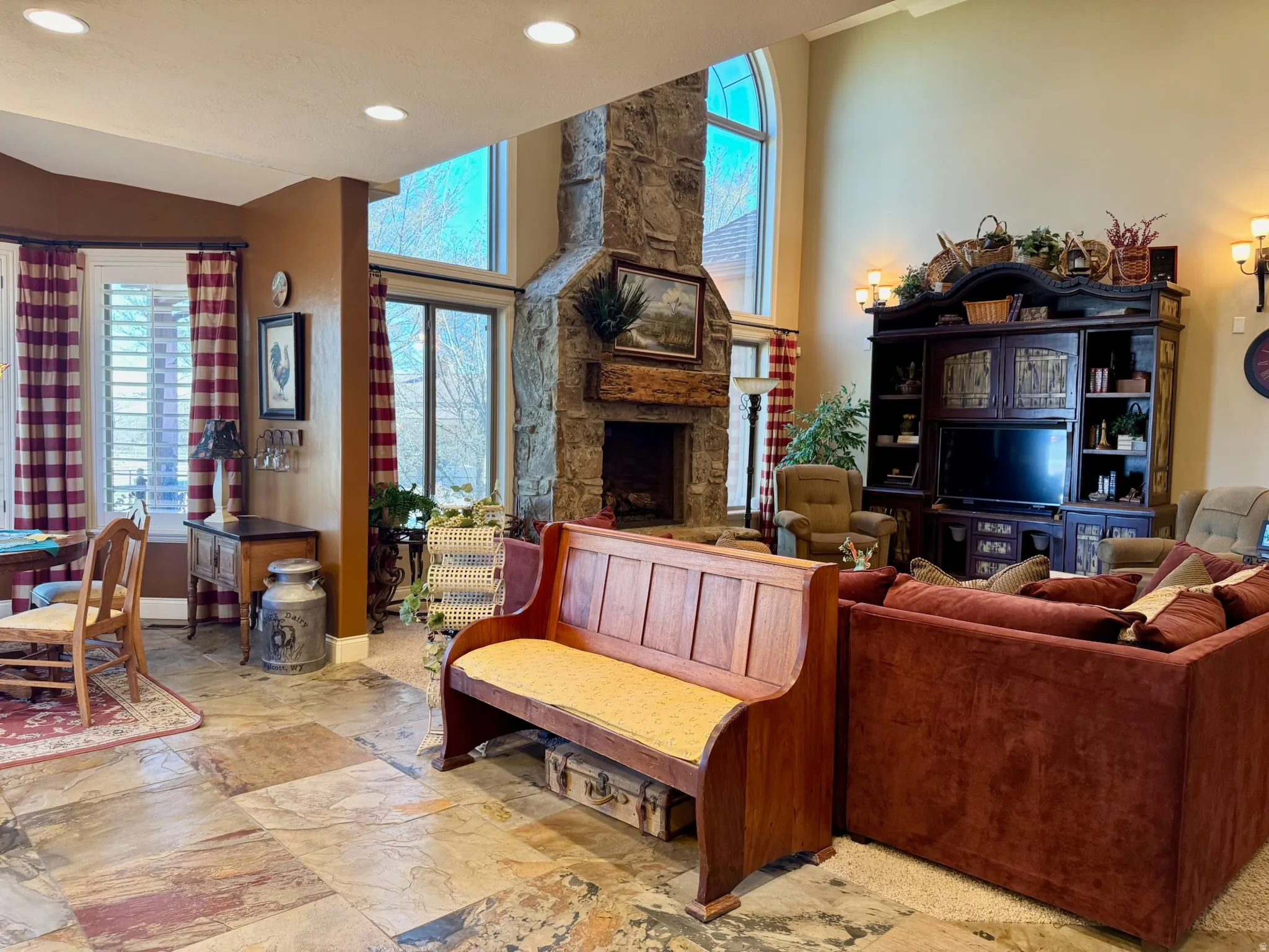 Living room featuring recessed lighting, vaulted ceiling, a fireplace, and light stone finish flooring