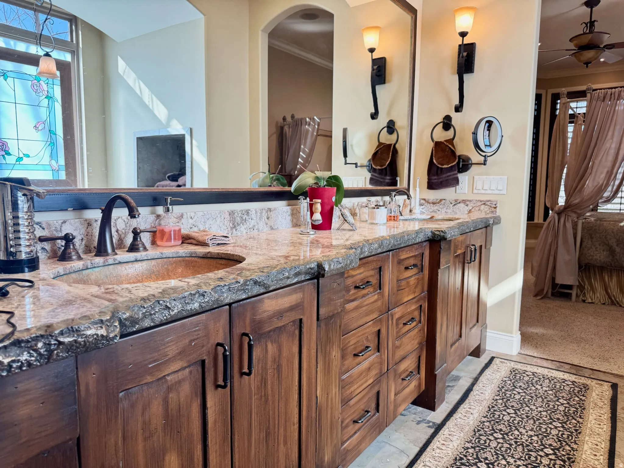 Ensuite bathroom with plenty of natural light, double vanity, crown molding, and a ceiling fan