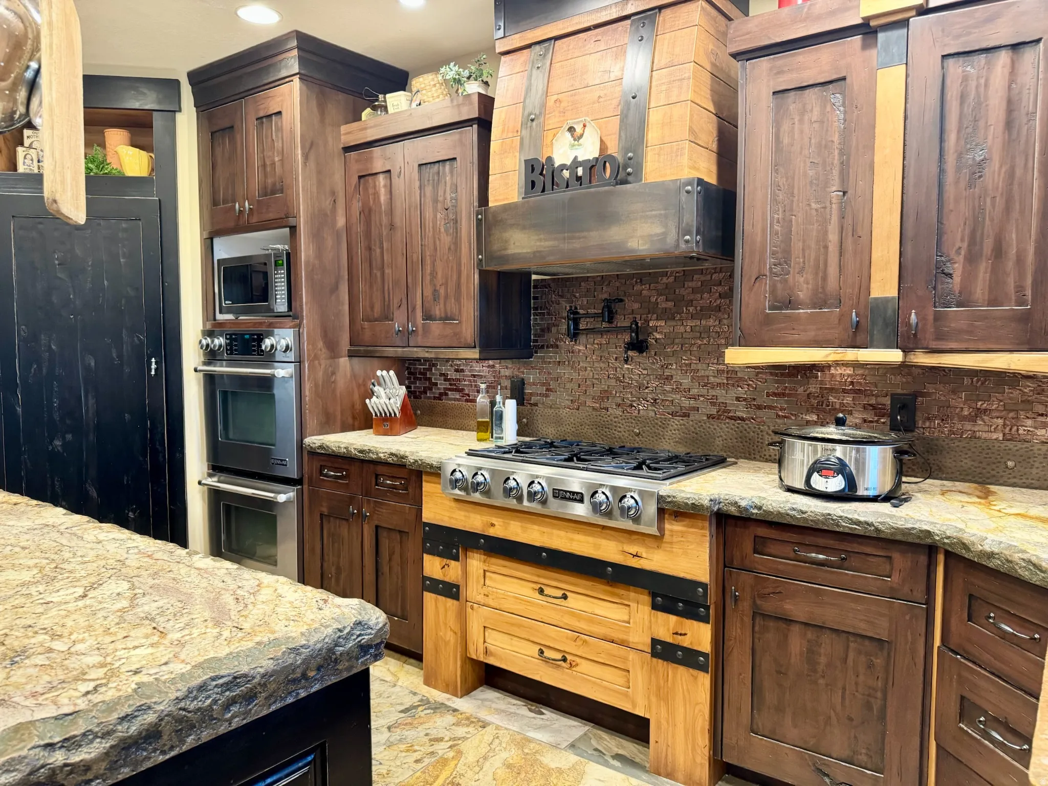 Kitchen with light stone counters, stainless steel appliances, and backsplash