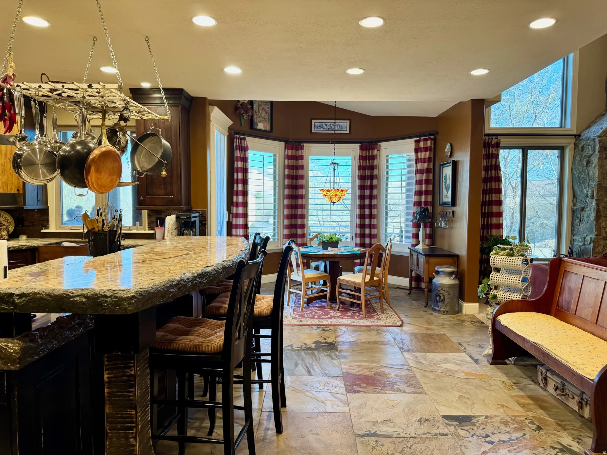 Kitchen featuring recessed lighting, stone tile floors, dark wood finish cabinetry, light stone counters, and vaulted ceiling