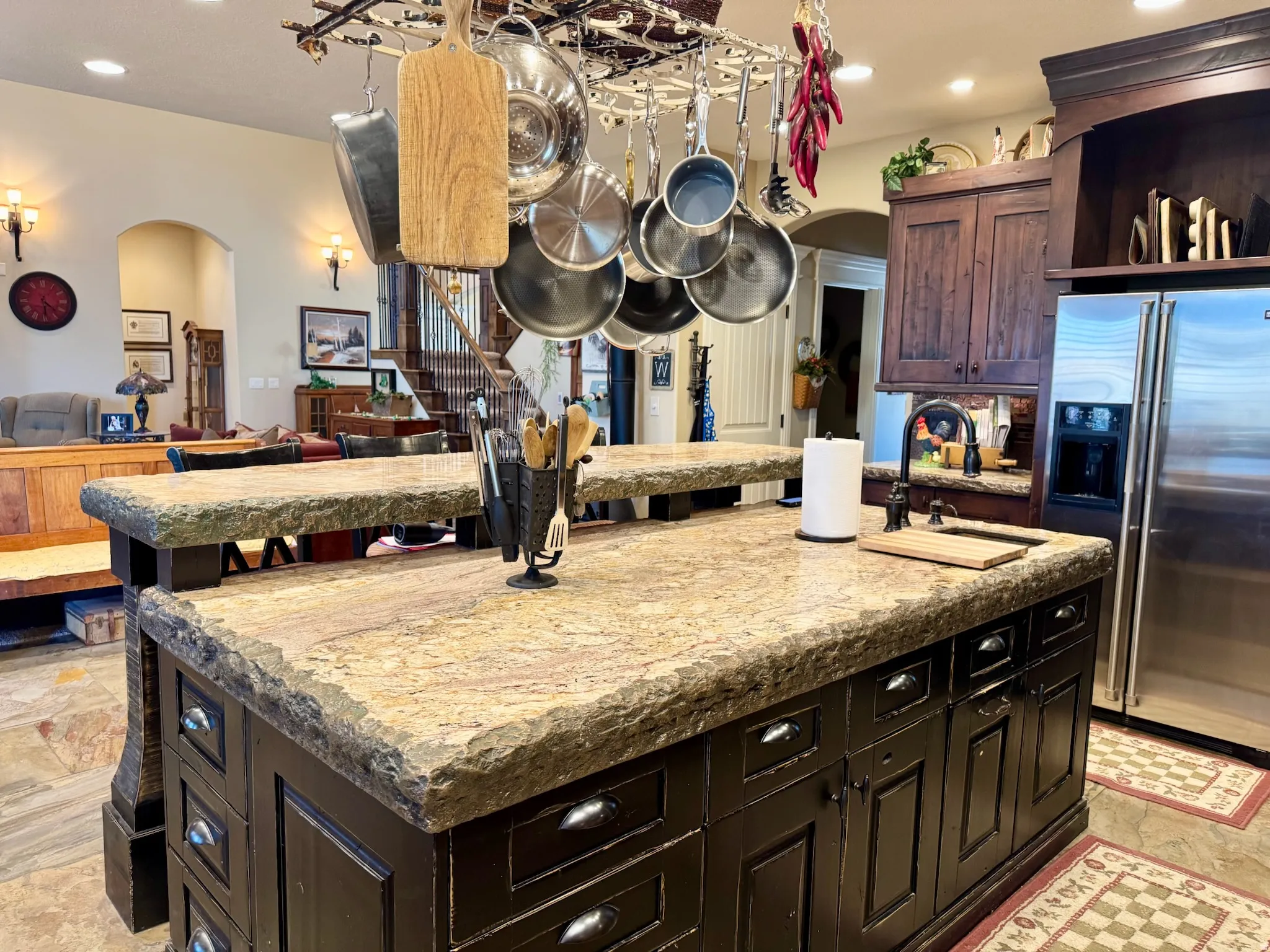 Kitchen with arched walkways, dark wood finish cabinets, high end refrigerator, open floor plan, and recessed lighting