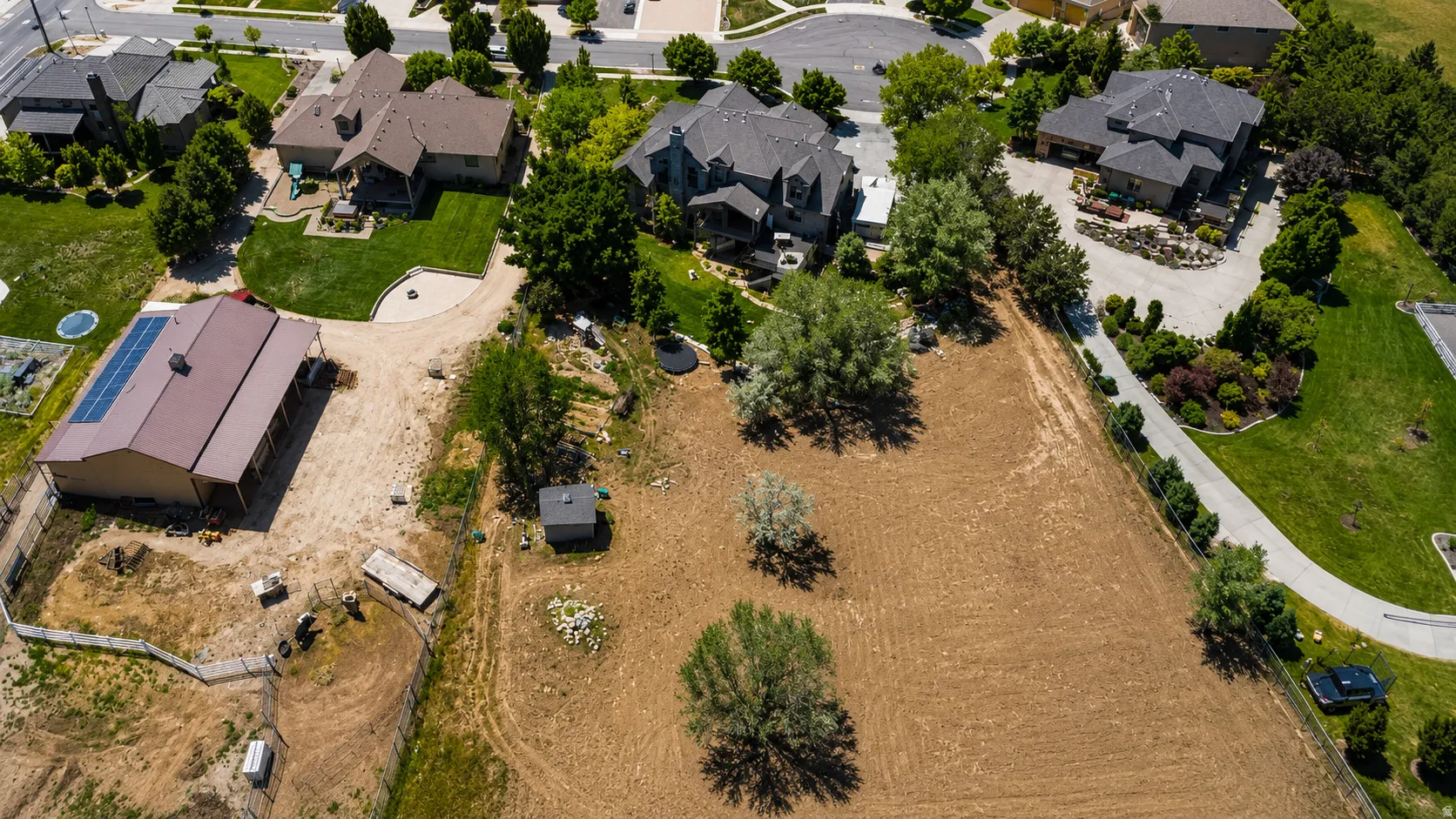 Expansive land parcel featuring open fields, mature trees, and a detached outbuilding with solar panels
