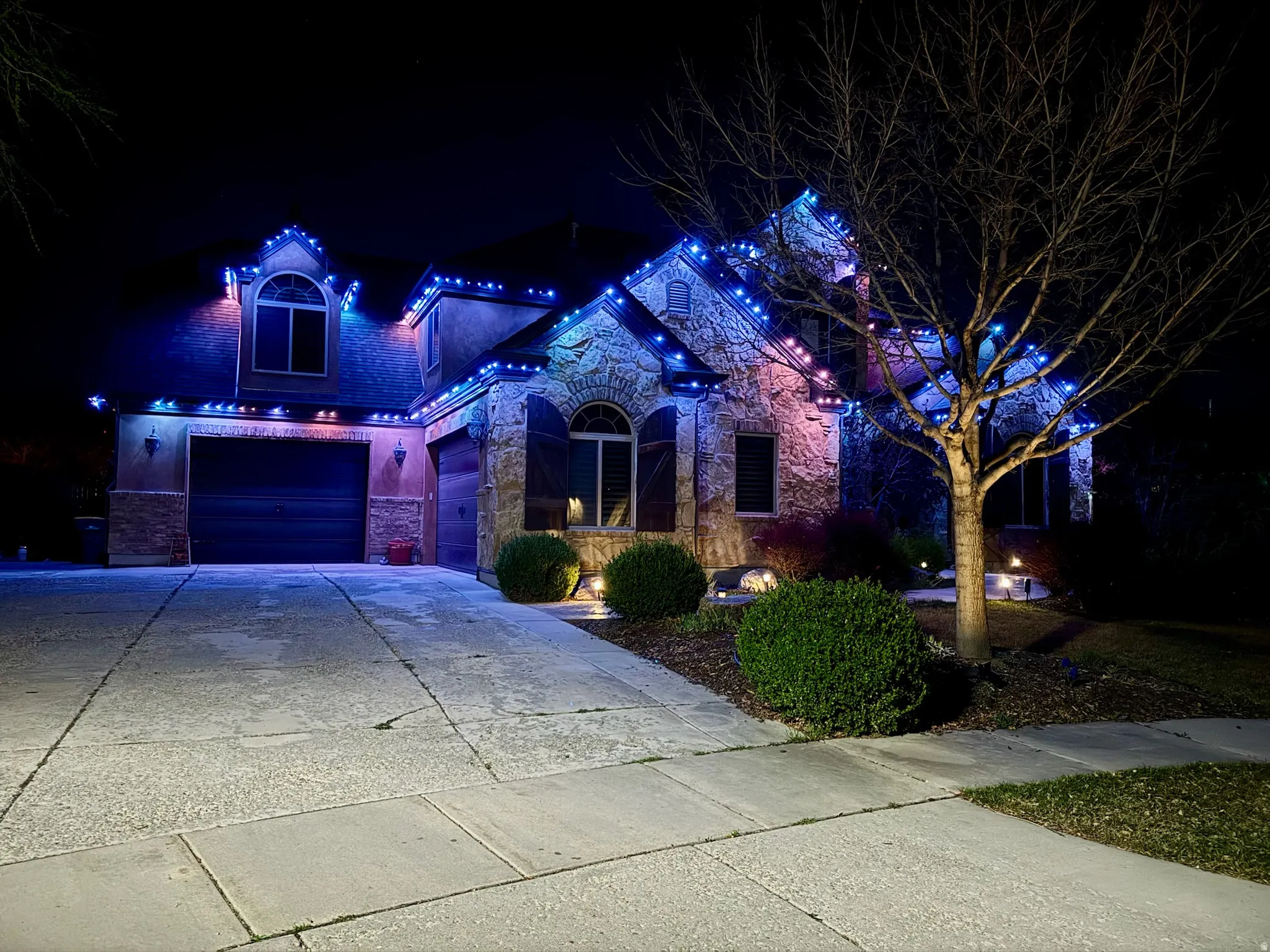 View of front of home featuring driveway, stone siding, brick siding, and an attached garage