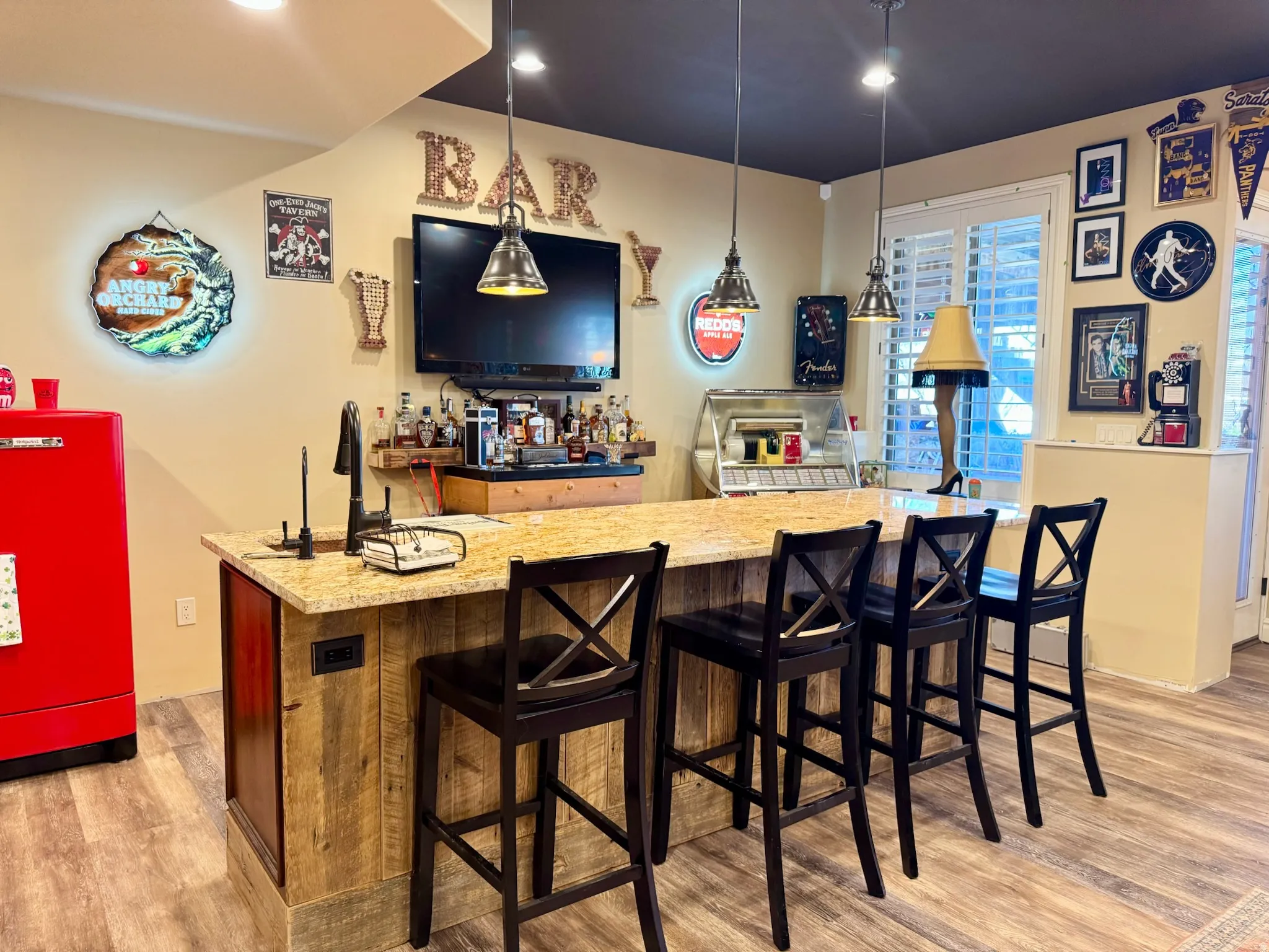Indoor wet bar featuring light wood-type flooring, light stone counters, and decorative light fixtures