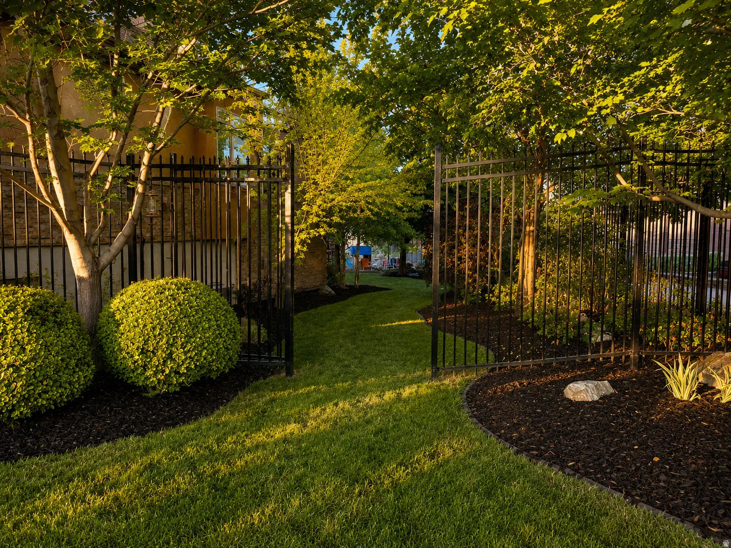Manicured lawn with black wrought iron fencing and gates