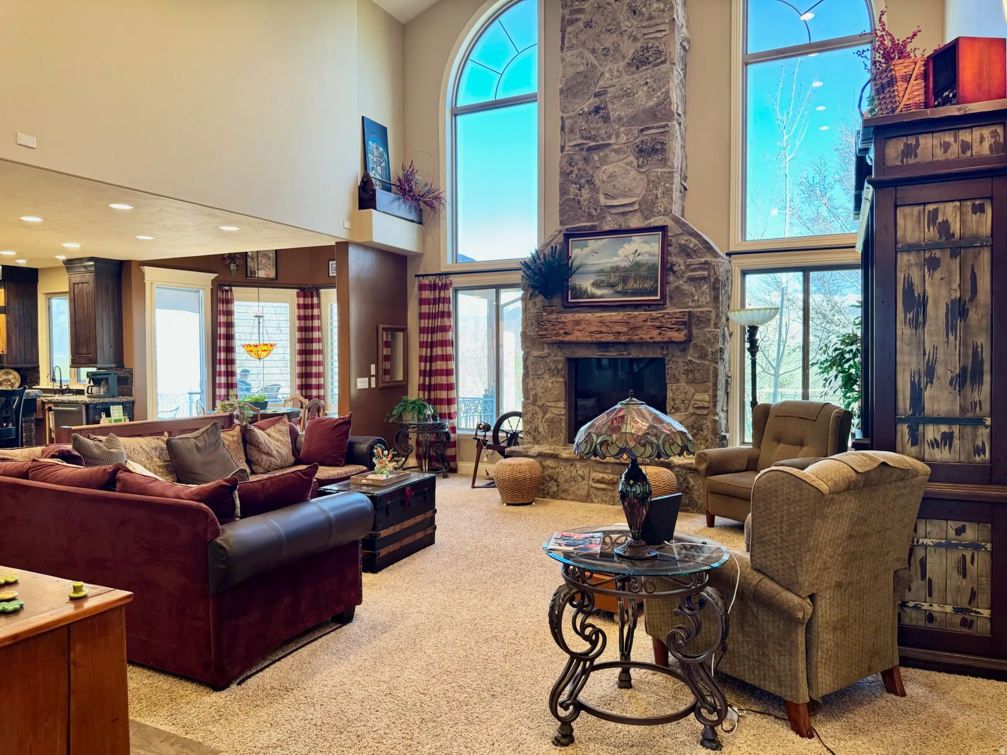 Living room with light carpet, a high ceiling, and a stone fireplace