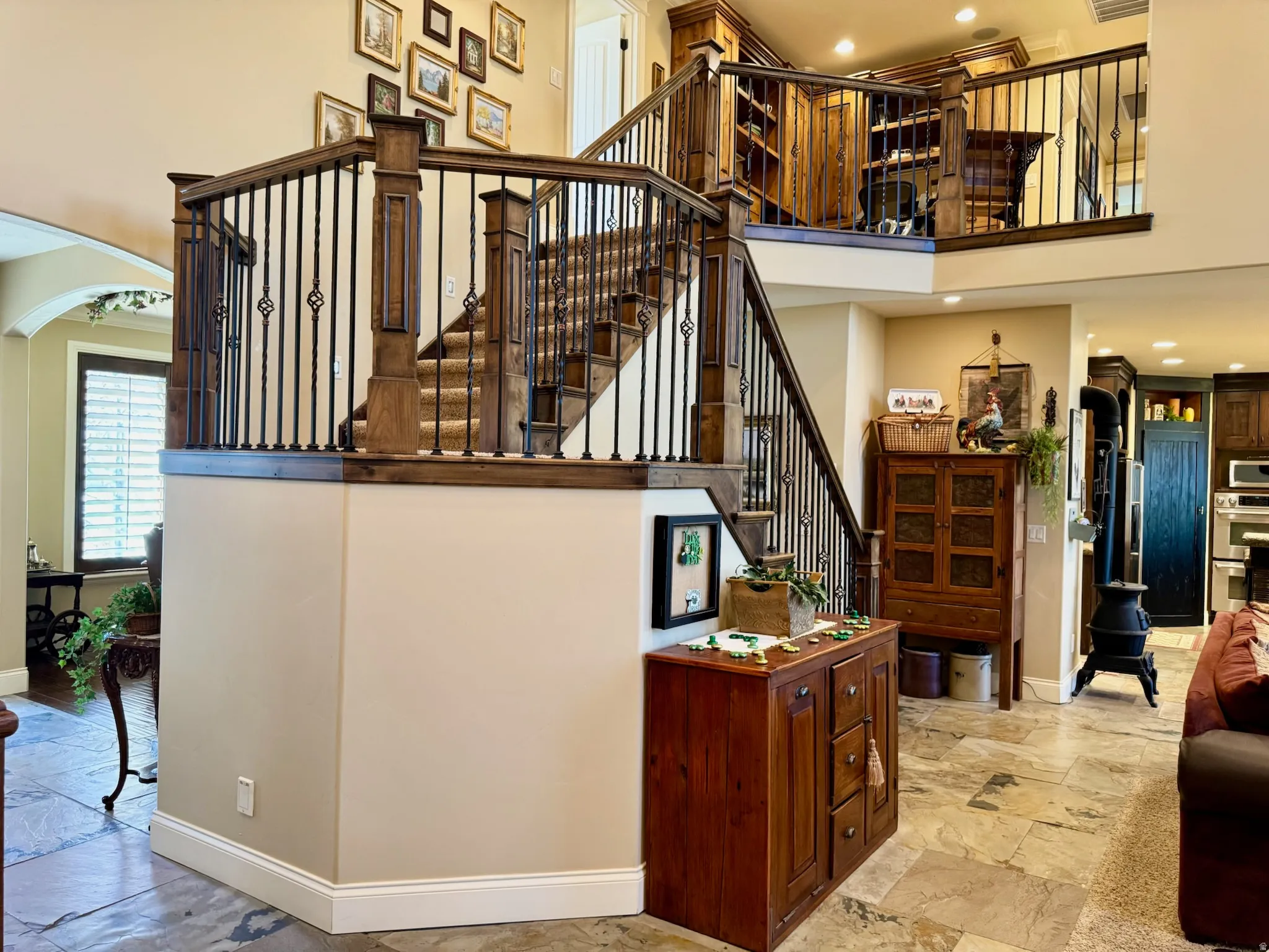 Stairway with arched walkways, a high ceiling, stone tile flooring, and recessed lighting