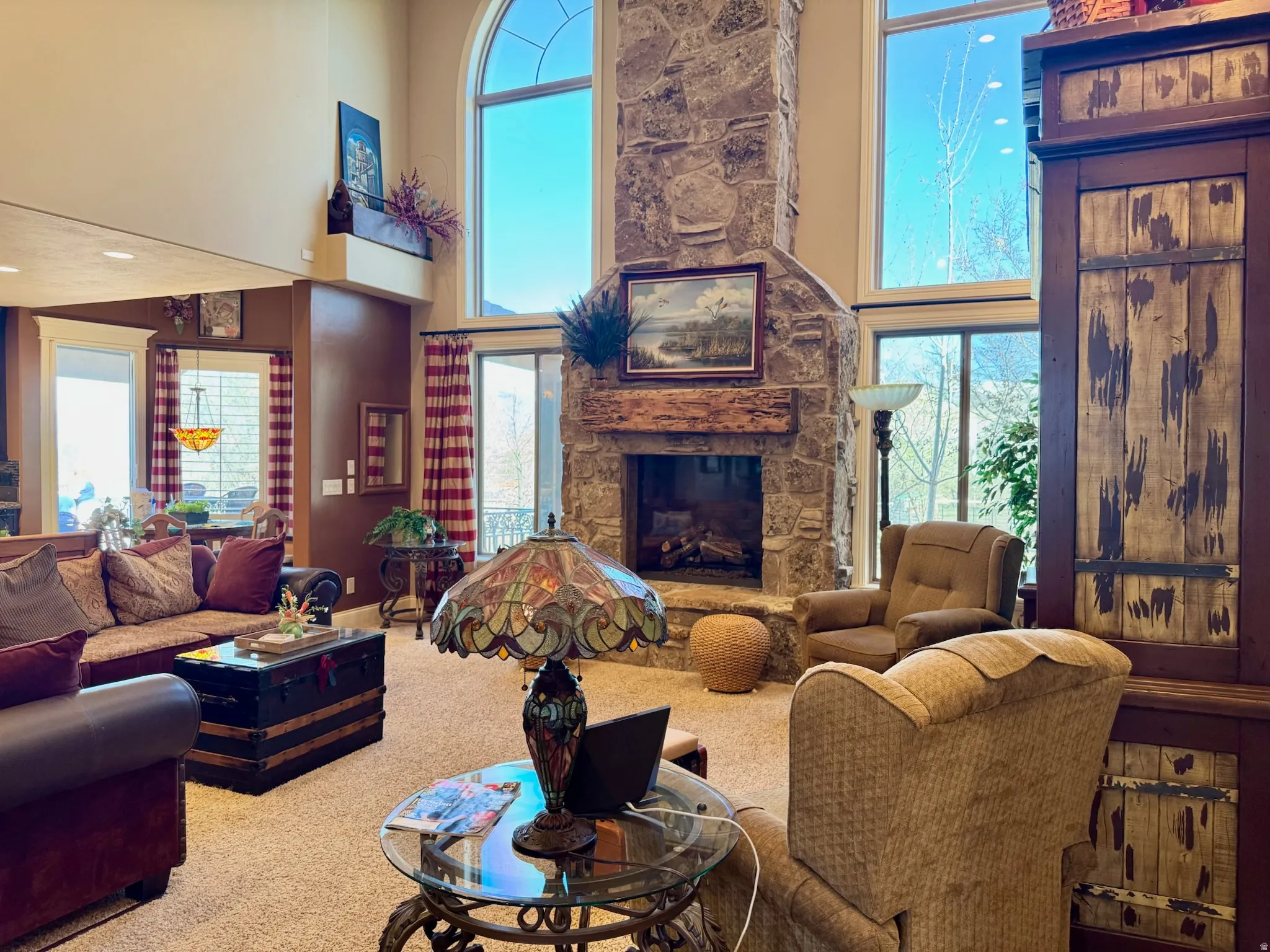 Carpeted living room featuring a high ceiling, a fireplace, and healthy amount of natural light