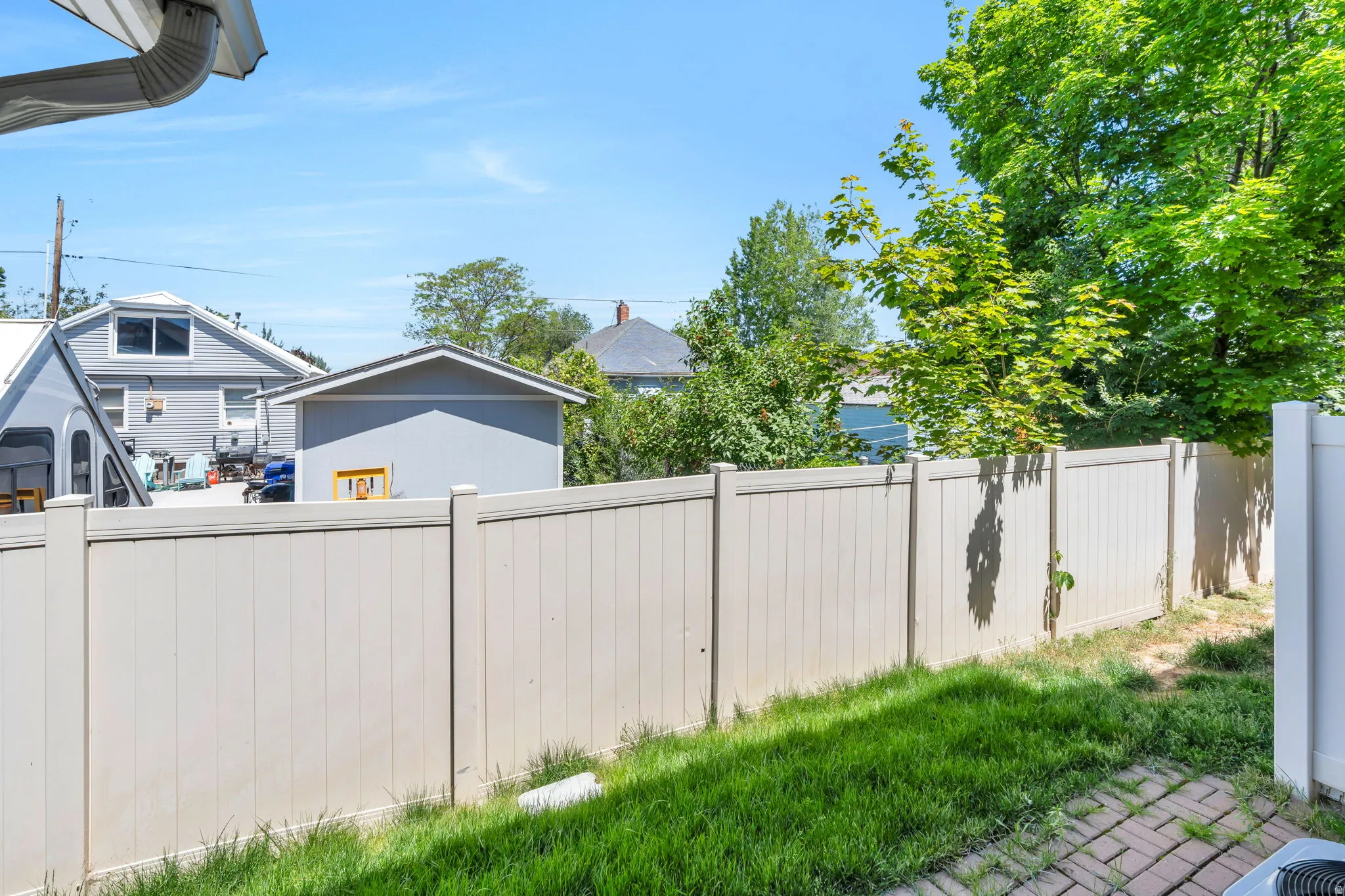 Fenced outdoor space featuring a section of brick paver patio and a manicured lawn
