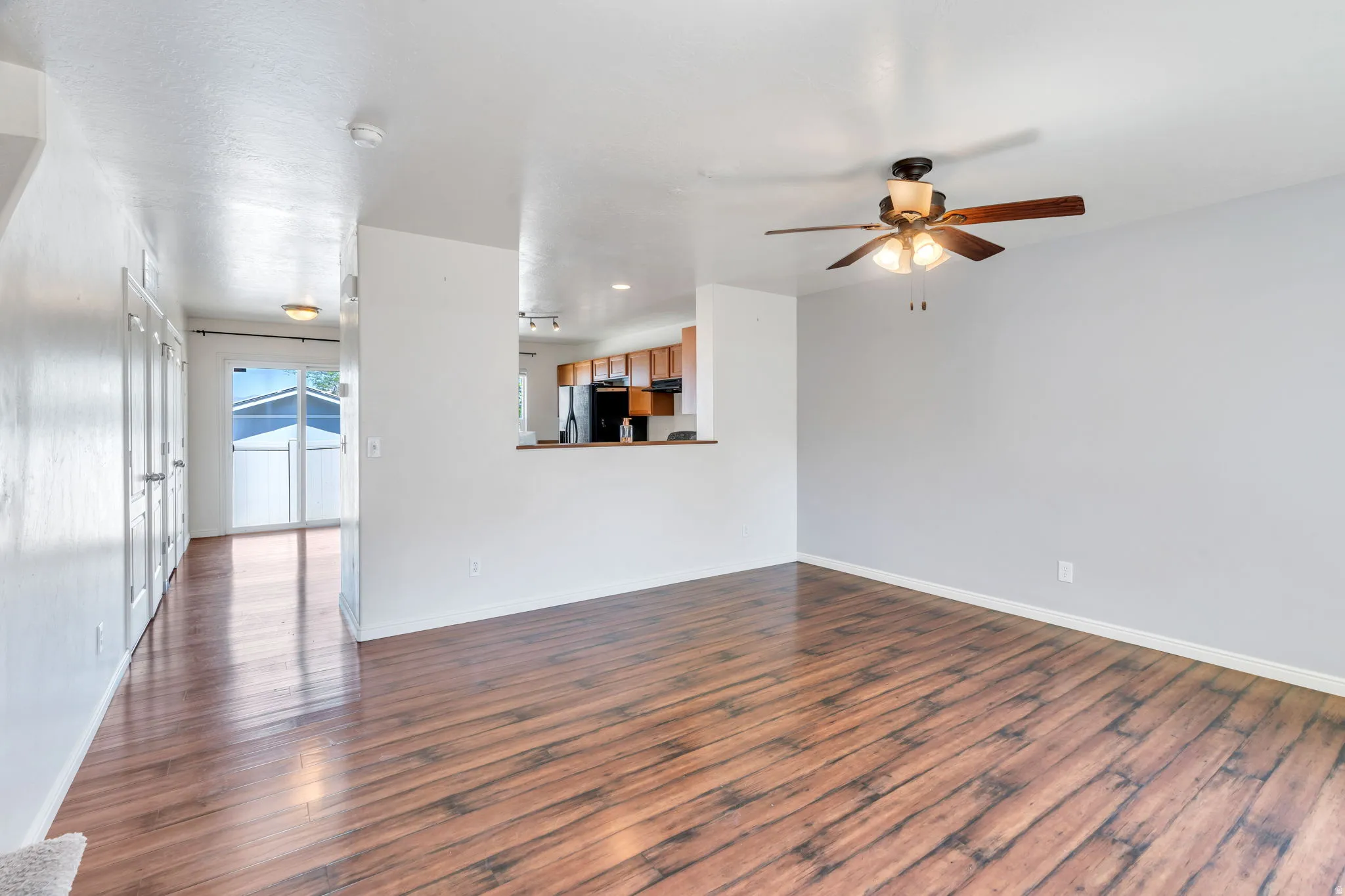 Open living area featuring wood-finish flooring, a ceiling fan with integrated lighting, and a neutral wall palette