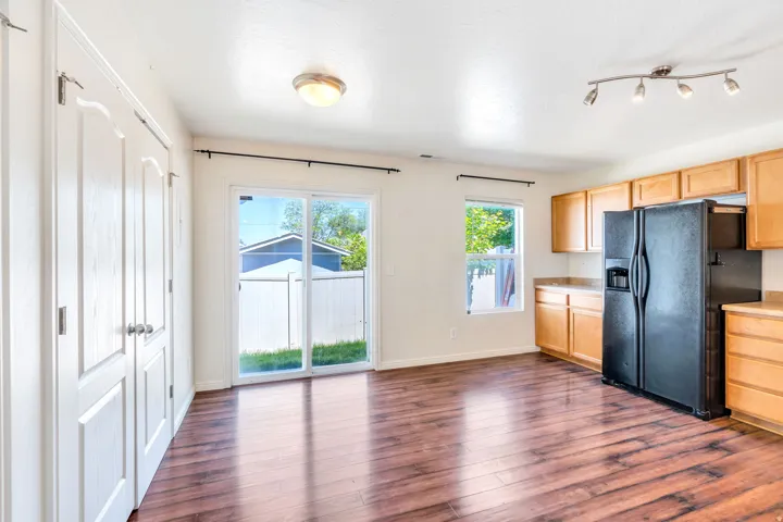 Open-concept kitchen and dining area featuring wood-finish flooring, a full suite of black appliances, and natural wood cabinetry