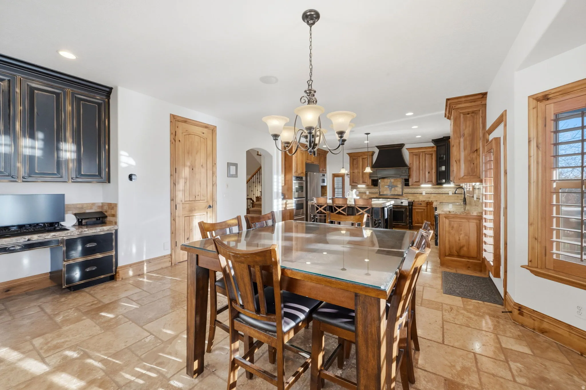 Dining room with stone tile flooring, arched walkways, and suspended lighting