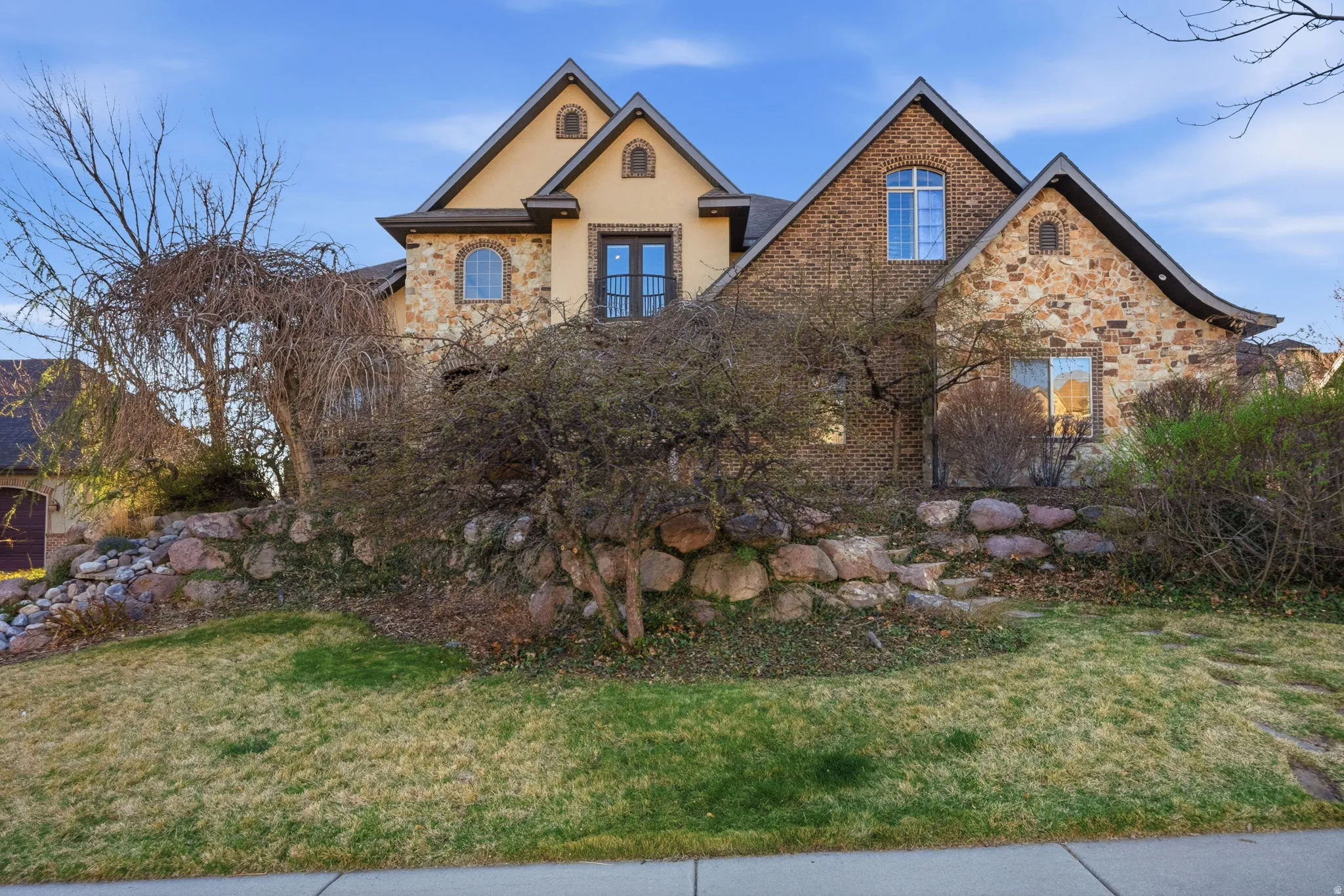 View of front facade with a front lawn, stone siding, and stucco siding
