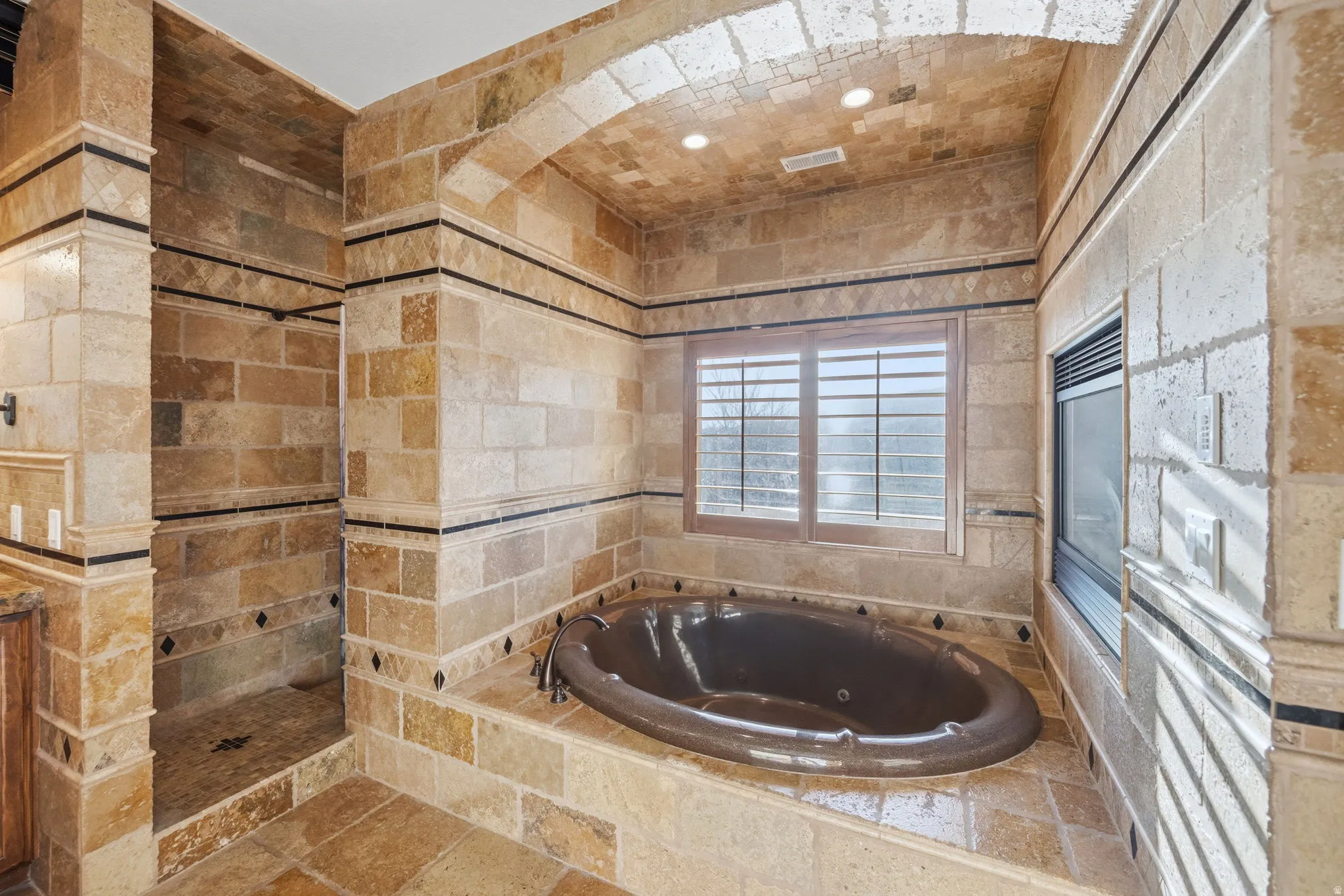 Bathroom with a jetted tub, a walk in shower, and tile walls