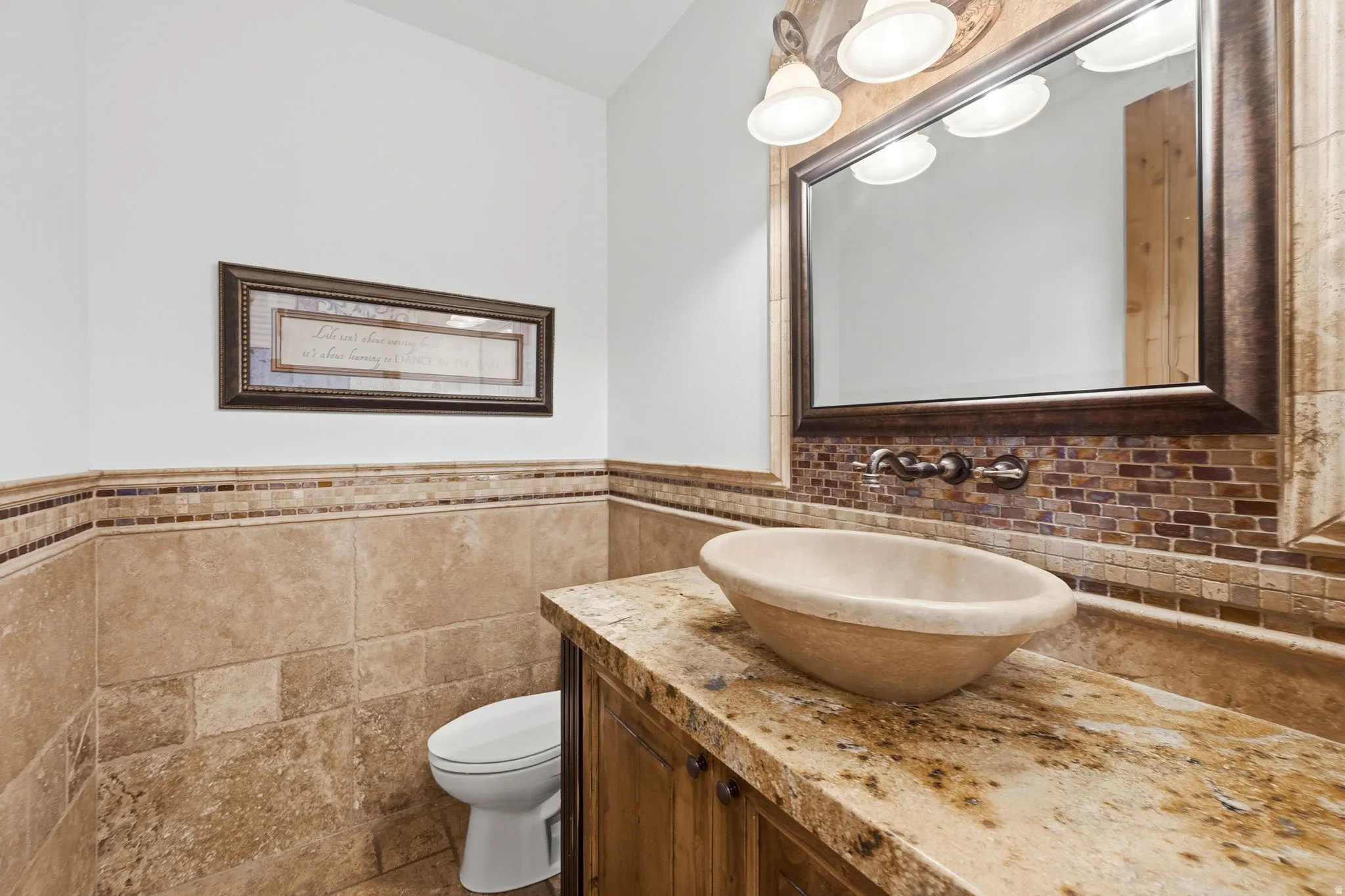 Bathroom featuring vanity, a wainscoted wall, and tile walls