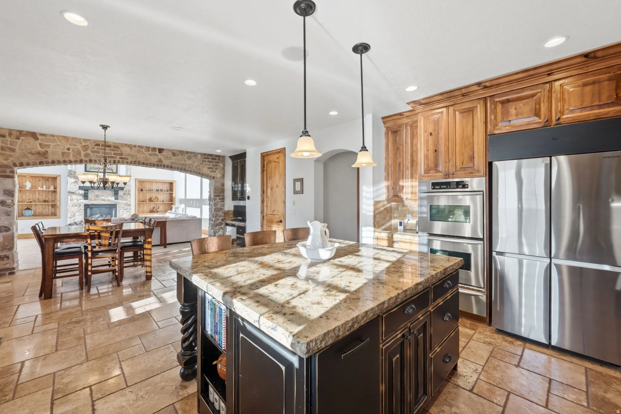 Kitchen featuring a kitchen island, stone tile flooring, stainless steel appliances, and arched walkways