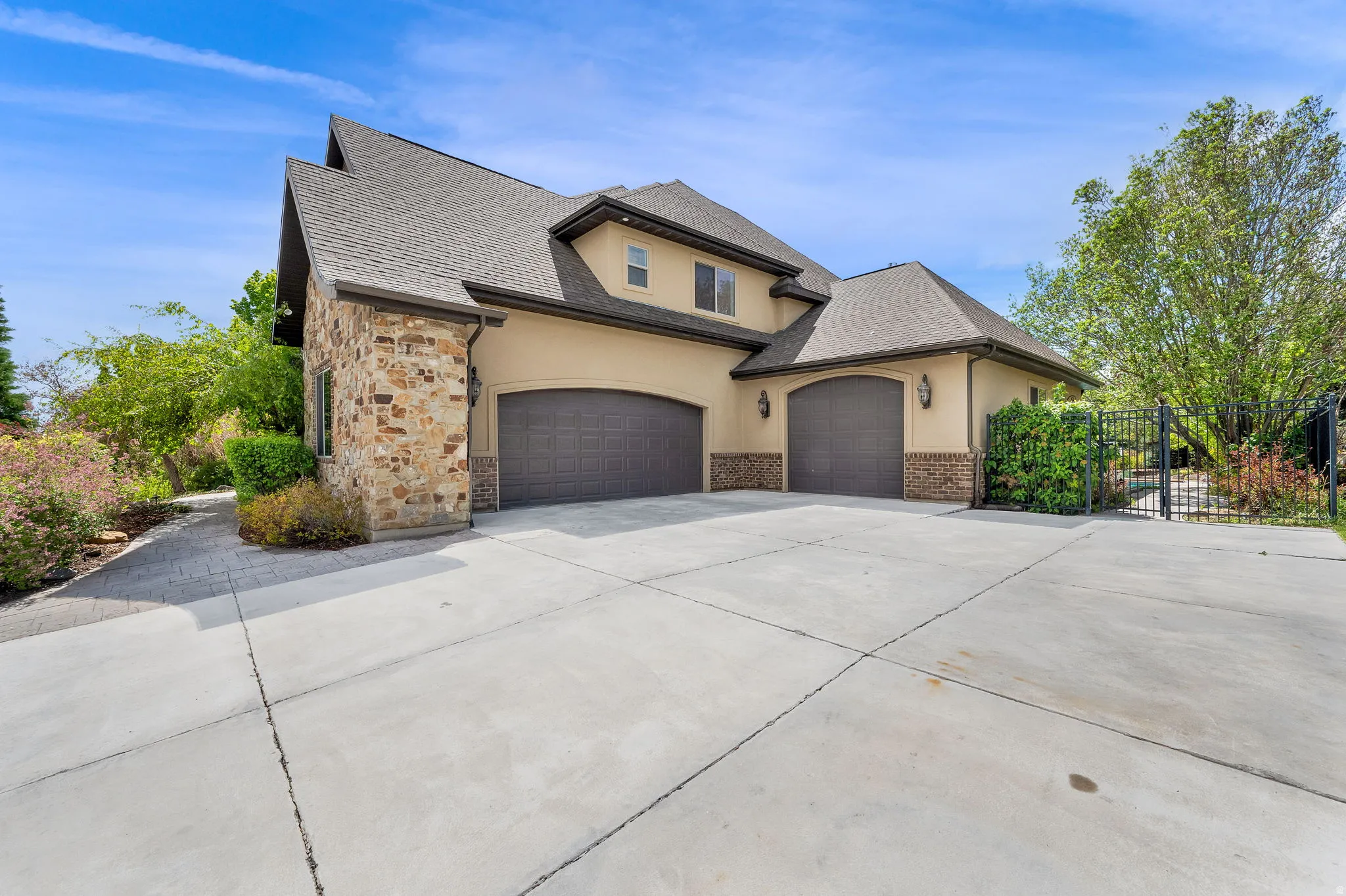 French country style house featuring stucco siding, driveway, an attached garage, stone siding, and roof with shingles