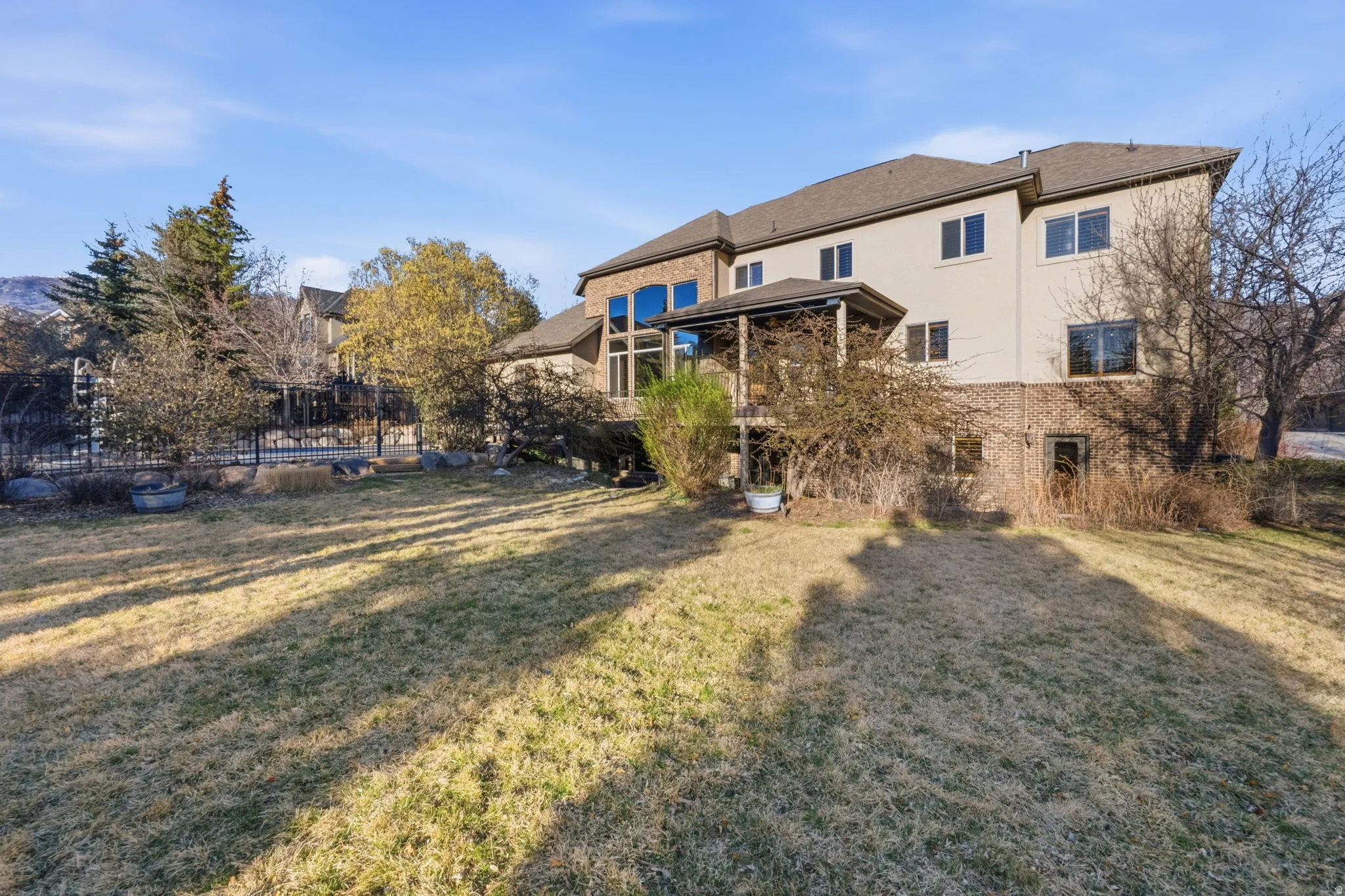 Back of property featuring a lawn, stucco siding, a balcony, and brick siding